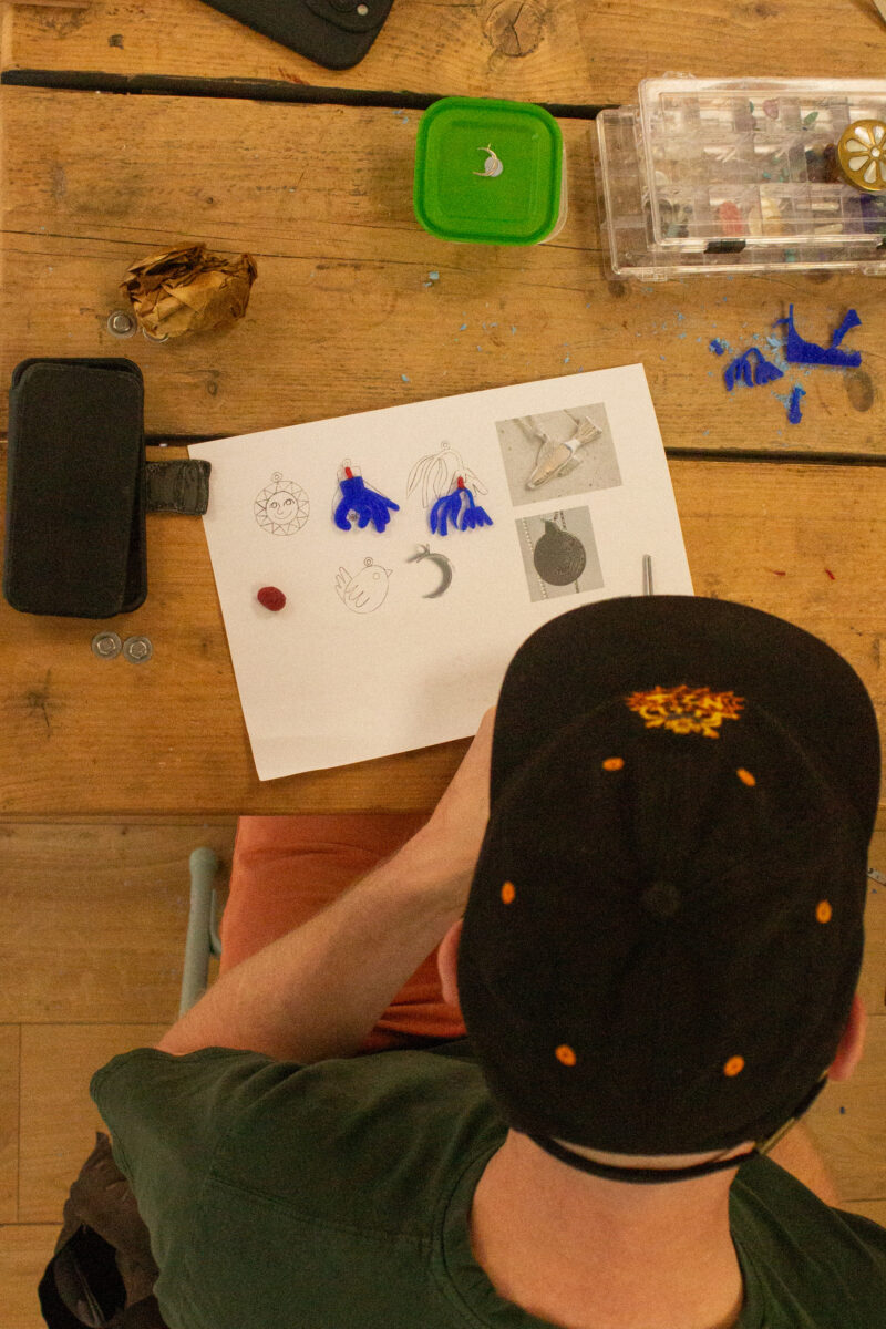 someone is planning out their jewellery designs using illustration and then carving in wax
