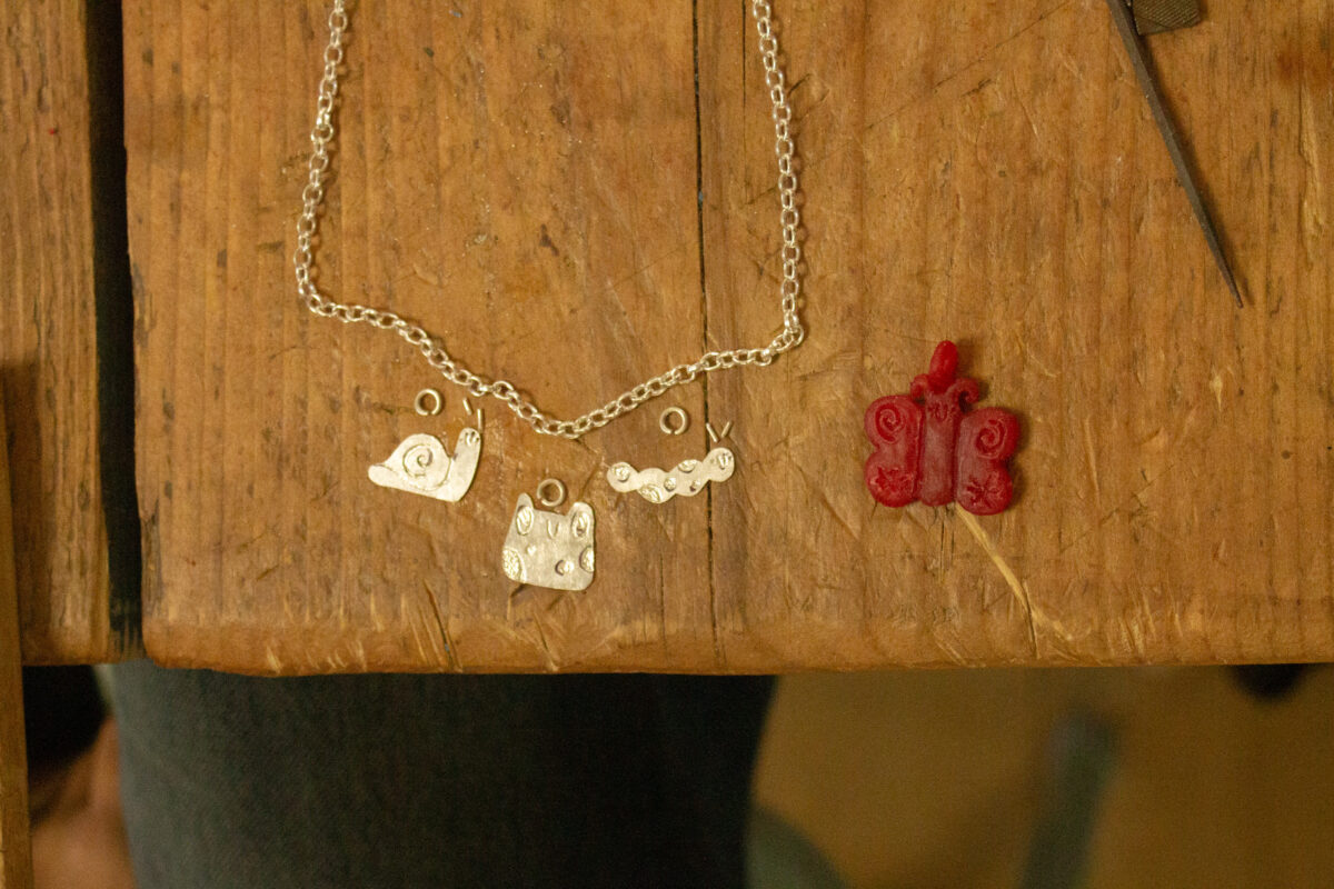 a flat lay of silver charms hand engraved and a wax butterfly in a fun illustrative style