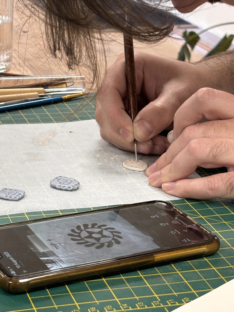 someone copies an image on their phone for a design onto their silver clay
