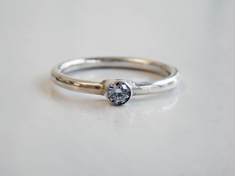 cubic zirconia tube set into a silver ring on a white background