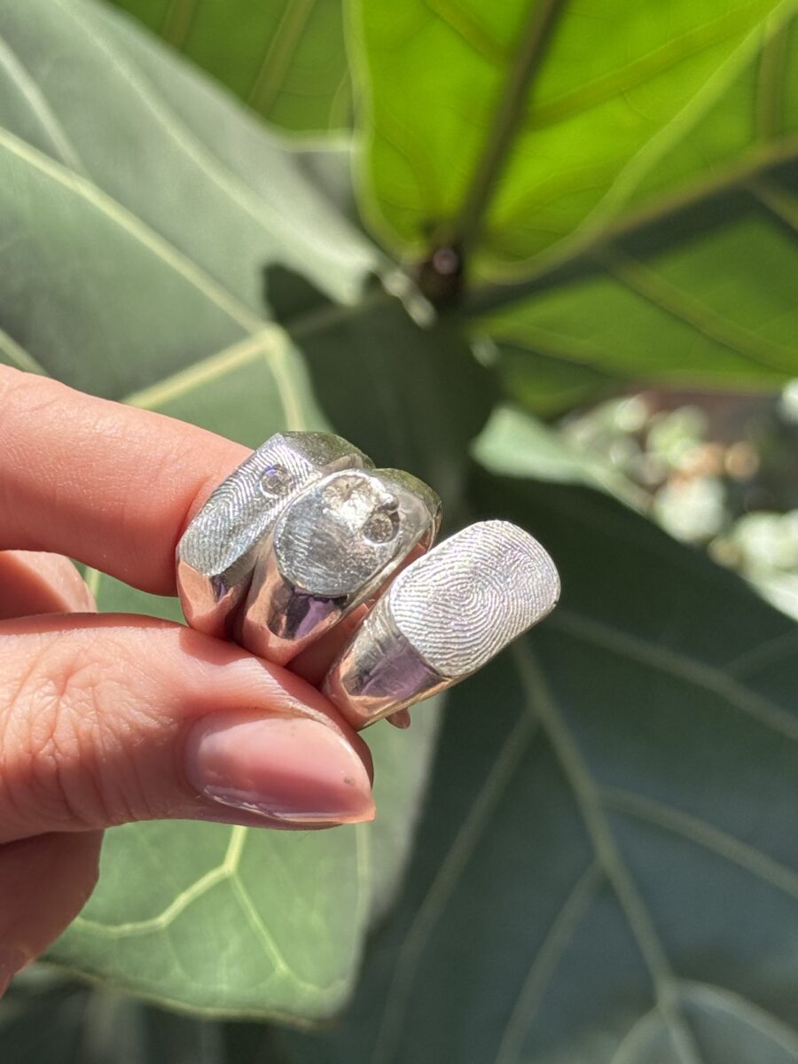 set of three signet rings in silver. Two have fingerprint detail on top white one has a small gemstone set into it