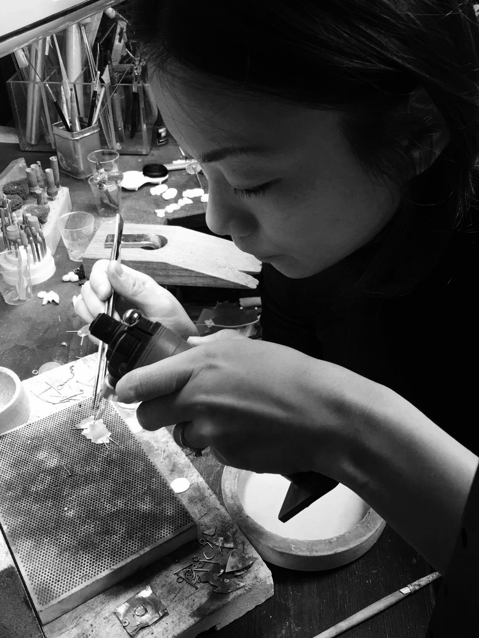 Jeweller soldering something small on a soldering block on a jewellers bench